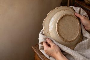欠けのある大皿を柔らかな布で包み、底面を確かめる手元